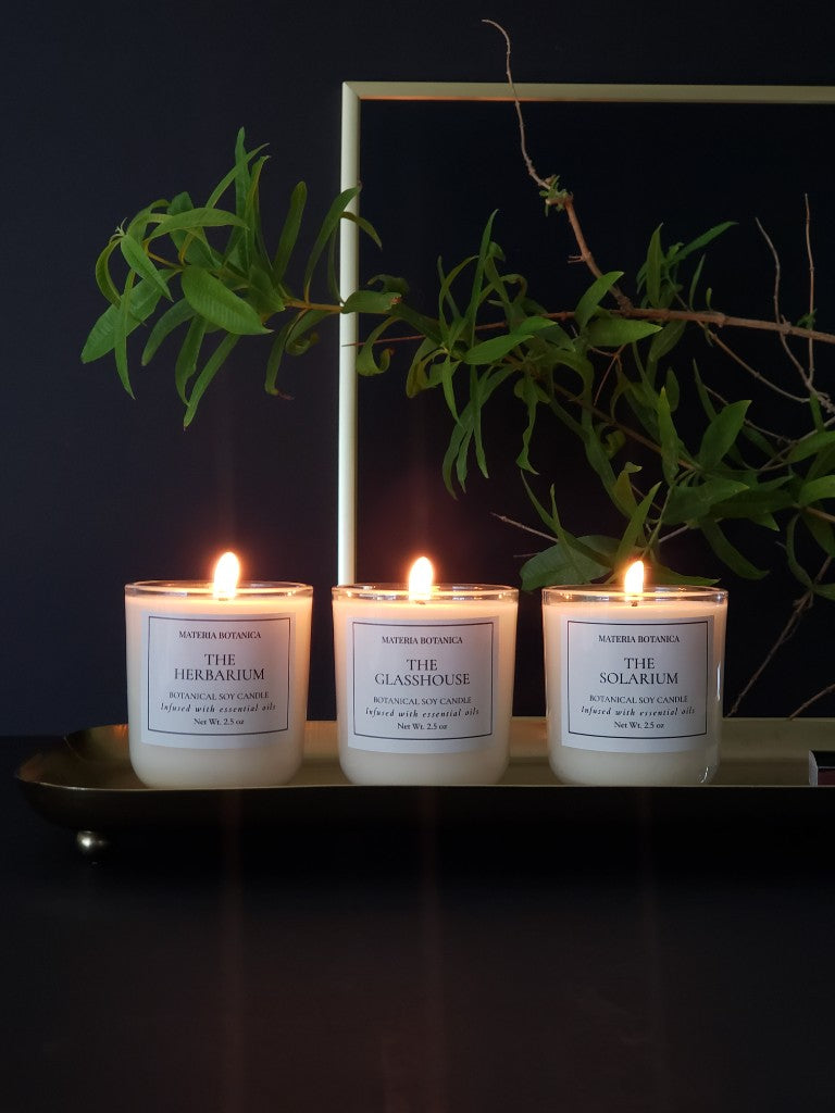 Mini Trio Gift Set: The Herbarium, The Glasshouse, and The Solarium lit on a brass tray
